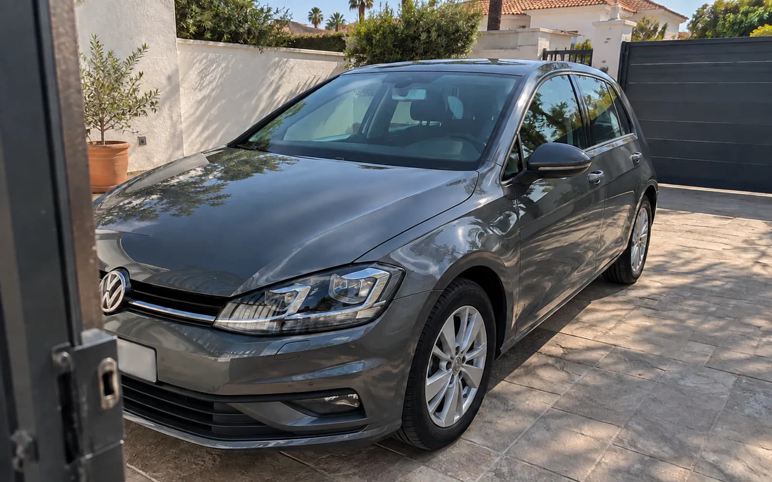 Golf gris estacionado en una entrada residencial visto desde el acceso